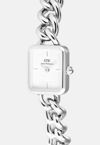 Viereckige Uhr mit weißem Zifferblatt und silbernem Gliederarmband, ausgestattet mit minimalistischen Stundenmarkierungen und einem Logo. Polierte Metalloberfläche.