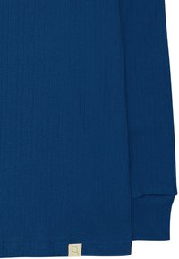 Maglietta a maniche lunghe a coste di colore blu scuro. Tessuto morbido, scollatura arrotondata e un piccolo etichetta con un numero verde chiaro all'orlo.