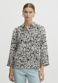 Knoop-up shirt van lichte stof, met een zwart en crème abstract patroon met blauwe accenten. Lange mouwen met zijsplitten aan de zoom.