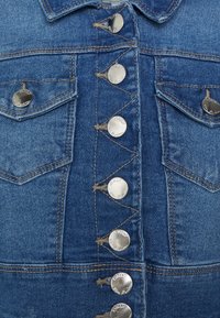 Denimklänning i ljusblått med knappstängning fram, rundad krage, två bröstfickor och metalldetaljer med ingraverat varumärke.