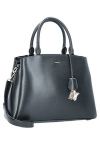 Czarna skórzana torebka DKNY z podwójnymi uchwytami, odczepianym paskiem na ramię i srebrnym charms'em z logo DKNY na białym tle.