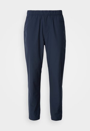 Pantaloni ușori, de culoare albastru marin, cu talie elastică, picioare conice și două buzunare laterale. Fabricati dintr-un material neted și rezistent.