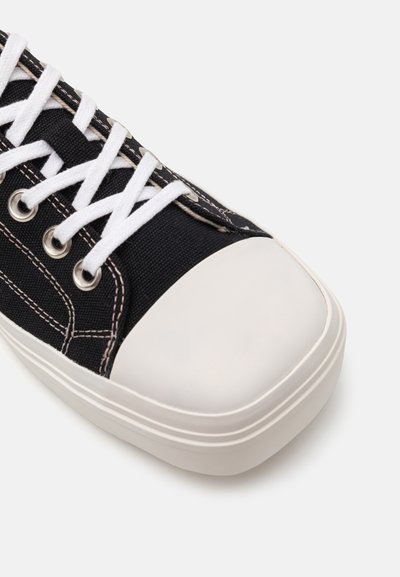 Sneaker in tela nera con punta in gomma bianca, lacci bianchi e cuciture a contrasto. Presenta occhielli in metallo e design con suola piatta.