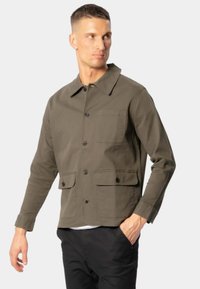 Oliven grøn jakke lavet af bomuld med knaplukning foran, krave, to frontlommer og en afslappet pasform. Struktureret stof med en mat finish.