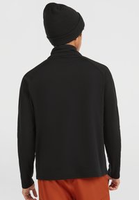 Zwarte lange mouwen shirt met een hoge kraag, gemaakt van een gladde, rekbare stof. Heeft raglanmouwen en een relaxte pasvorm.