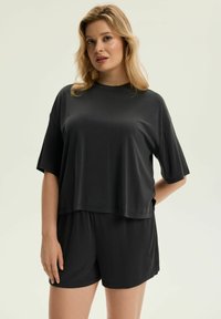 Czarny zestaw odzieży domowej składający się z luźnej bluzki z krótkim rękawem i pasujących szortów. Gładki, lekki materiał o swobodnym kroju i minimalistycznym designie.