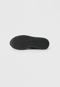 Talpă de cauciuc neagră, cu un model texturat de profunzime și cu brandul "Tommy Hilfiger" pe un fundal alb simplu.