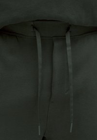 Tmavozelené teplákové nohavice s jemnou textúrou, elastickým pásom a zodpovedajúcimi šnúrkami so plastovými koncami.