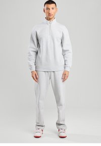 Gray fleece zip-up sweatshirt with high collar, paired with matching gray sweatpants. Both items feature elastic cuffs and waistband.