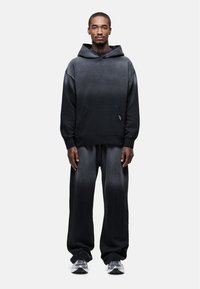 Hooded sweatshirt en broekset in zwart ombré ontwerp, met zachte stof, voorzak en een relaxte pasvorm. Accentuated met een logopatch.