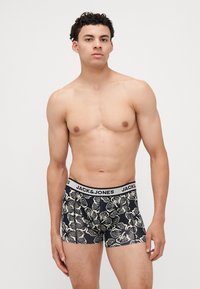Fekete boxer alsónadrág virágmintával krémszínben, rugalmas derékkal, amelyen fehér szöveggel szerepel a "JACK & JONES" felirat.