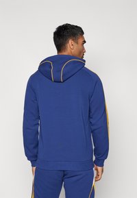 Blue hoodie with a yellow accent along the hood and sleeves, featuring a soft texture and a relaxed fit. No visible logos or patterns.
