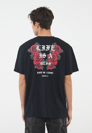 Maglietta nera in cotone con una grafica di rose rosse e testo sul retro. Maniche corte e vestibilità comoda.