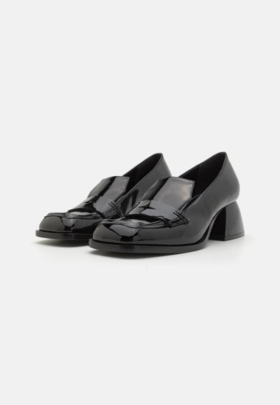 Black patent leather shoes with a low block heel, rounded toe, and a folded accent at the front. Smooth, shiny texture.