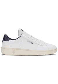 Vit lädersneaker med en marinblå häldel, platta snören och strukturerad krämfärgad sula. Har logotyp och "SINCE 1966" präglat i guld.