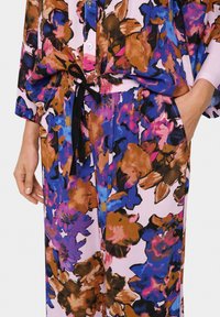 Set za prosti čas s cvetličnim vzorcem v roza, modrih in rjavih odtenkih. Ohlapen kroj z srajco na gumb in elastičnim pasom. Ima črno vrvico.