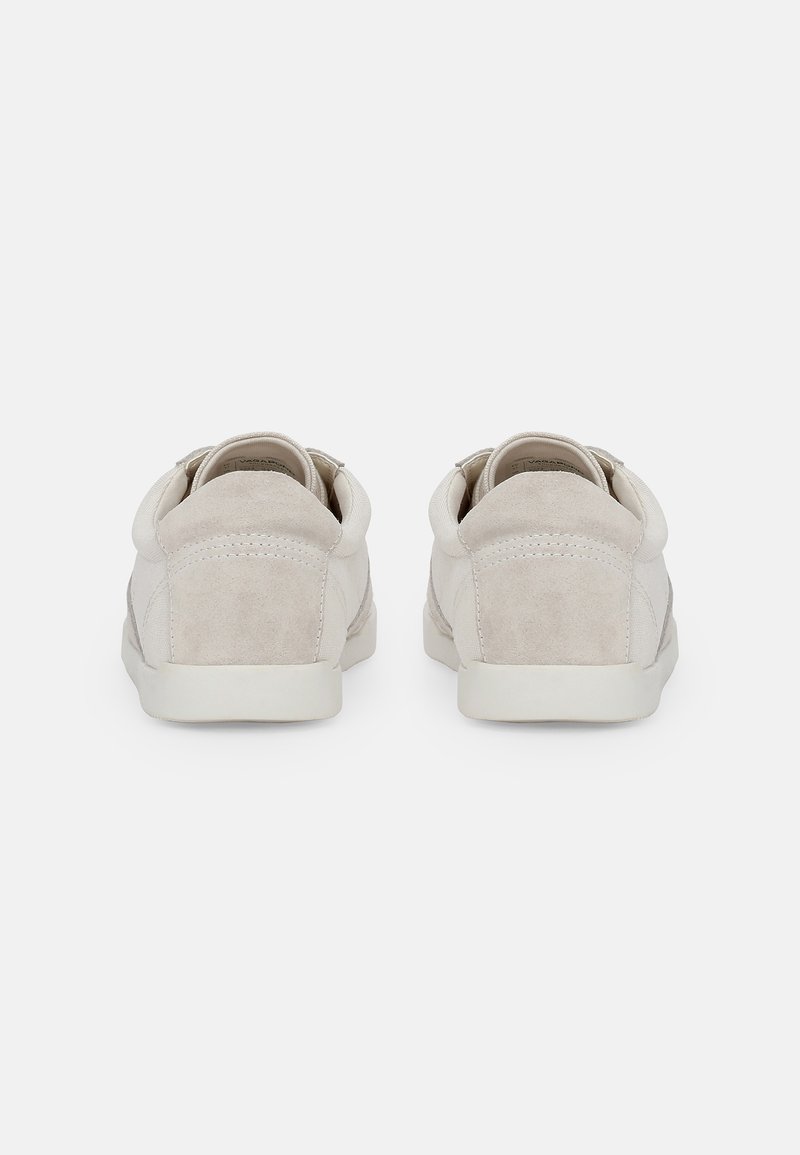 Dwa jasnobeżowe zamszowe sneakersy o niskim profilu, zaokrąglonym nosku i minimalistycznym designie. Teksturowane boki i miękka podszewka z tkaniny.