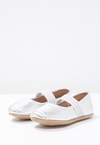 Sølvmetalliske ballet-sko med bred elastisk stropp og myk beige sole. Glatt tekstur med rund tå-design.