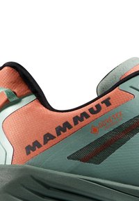 Grüne und Korallen-Sneaker mit strukturiertem Obermaterial, schwarzen Akzenten und Logo. Verfügt über ein GORE-TEX-Label und Mesh-Details für Atmungsaktivität.