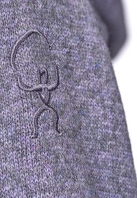 Strikket sweater i nuancer af grå og lilla med en blød tekstur. Har et broderet logo i mørkegrå på stoffet.