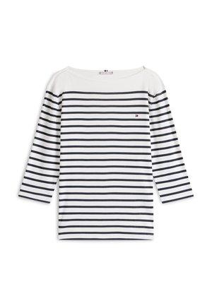 Λευκό πουκάμισο με μακριά μανίκια και οριζόντιες ναυτικές ρίγες. Διαθέτει ευρύ ντεκολτέ και μικρό λογότυπο στο αριστερό στήθος. Μαλακή υφή υφάσματος.