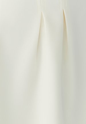 Crème-kleurige stof met plooien, een soepele textuur en een op maat gemaakte uitstraling. Het materiaal heeft een subtiele glans, wat de visuele diepte versterkt.
