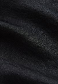 Schwarzer gewebter Stoff mit leichtem Glanz, der eine glatte Textur und subtile Farbvariationen aufweist, die eine Tiefe im Erscheinungsbild erzeugen.