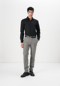 Black button-up shirt, patterned grey trousers, black belt, and black shoes. Slim fit design, smooth fabric, geometric pattern on pants.