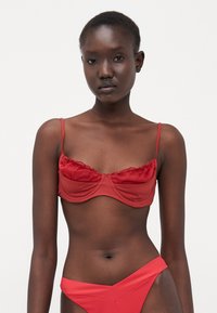Top in bikini rosso con tessuto morbido, design con ferretto, bordi arricciati e spalline sottili regolabili, abbinato a un pantalone alto coordinato.