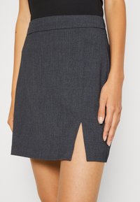 Falda de tela gris con corte recto, ligera abertura lateral y una cinturilla suave. El material tiene una textura sutil.