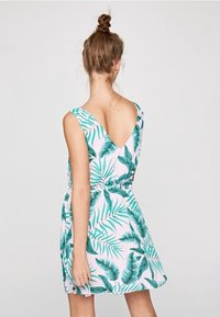 Vestido floral en pastel rosa con patrones de hojas verdes, diseño sin mangas, espalda en forma de V y cintura elástica para un ajuste ceñido.