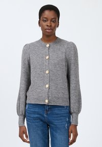 Cardigan grigio lavorato a maglia con scollatura rotonda, maniche lunghe a sbuffo e sei bottoni dorati a forma di conchiglia lungo il davanti. Finitura testurizzata.