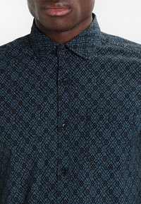 Korte mouwen overhemd met knopen in donkerblauw met een geometrisch zwart patroon, met een kraag en zwarte knopen aan de voorkant.