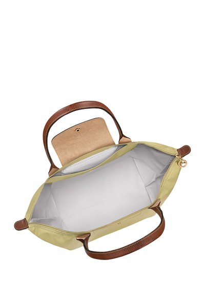 Large, light yellow handbag with brown textured handles. Interior is lined in white with a small beige pocket and snap closure.