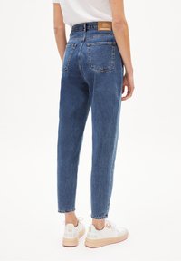 Jeans en denim bleu taille haute avec une coupe droite, dotés de cinq poches et d'une étiquette en cuir de marque au dos de la taille.