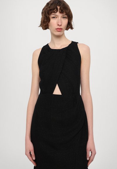 Vestido negro sin mangas con una tela texturizada, que presenta un corte delantero y un detalle drapeado en la cintura. El forro liso mejora el ajuste.