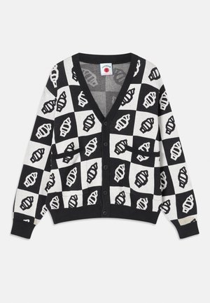 Cardigã cropped em preto e branco com decote em V, apresentando um padrão geométrico em concha, fecho com botões e dois bolsos frontais. Textura de malha suave.