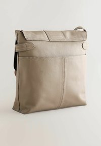 Beežist nahast kott tekstureeritud viimistlusega, millel on klapi sulgemine, kaks küljerihma ja tagaosa tasku. Siledad servad ja peen õmblusdetail.