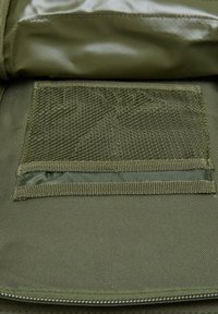 Olivgrön tyg med en texturerad meshnäsa och slät foder. Har förstärkta sömmar och en dragkedjeöppning.