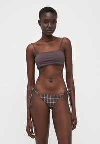 Dvodelni bikini set s trdnim rjavim braletom in spodnjim delom s karirastim potiskom ter nastavljivimi vezalkami, izdelan iz gladkega, elastičnega materiala.