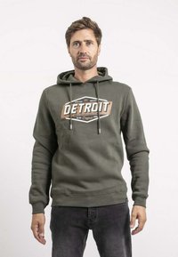 Sweat à capuche vert olive avec cordon de serrage, arborant un design graphique "DETROIT" en blanc et marron sur le devant, fabriqué à partir d'un tissu doux.