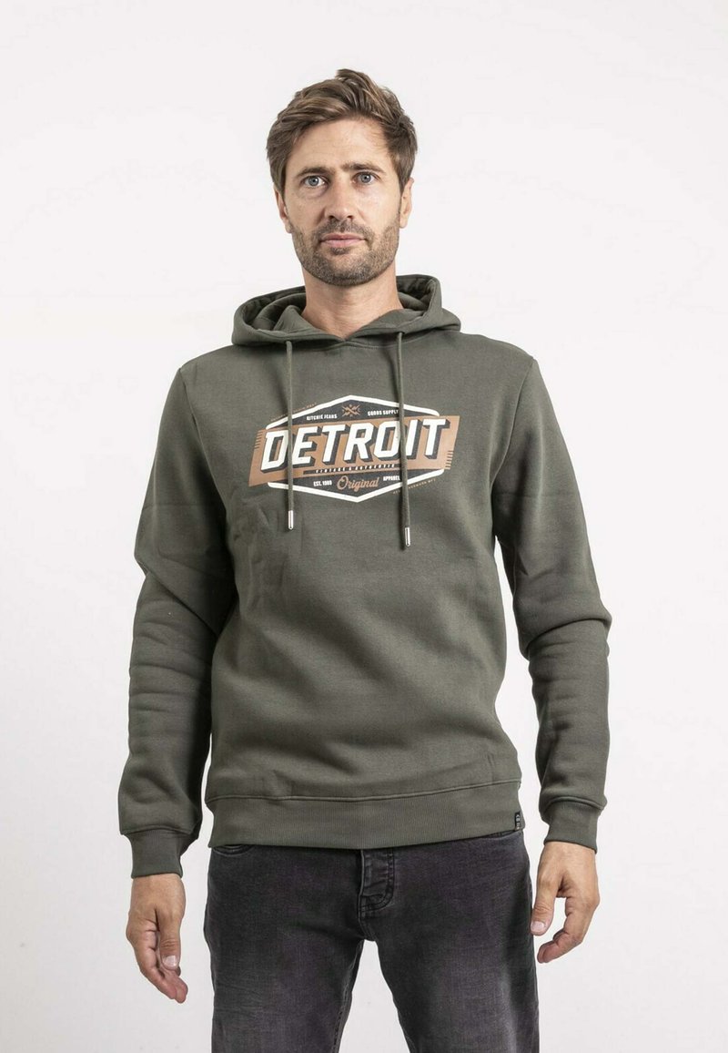 Sweat à capuche vert olive avec cordon de serrage, arborant un design graphique "DETROIT" en blanc et marron sur le devant, fabriqué à partir d'un tissu doux.