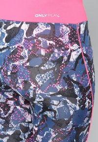 Leggings a vita alta con un motivo astratto e colorato nei toni del blu, nero e rosa, dalla texture liscia e un elastico rosa in vita.