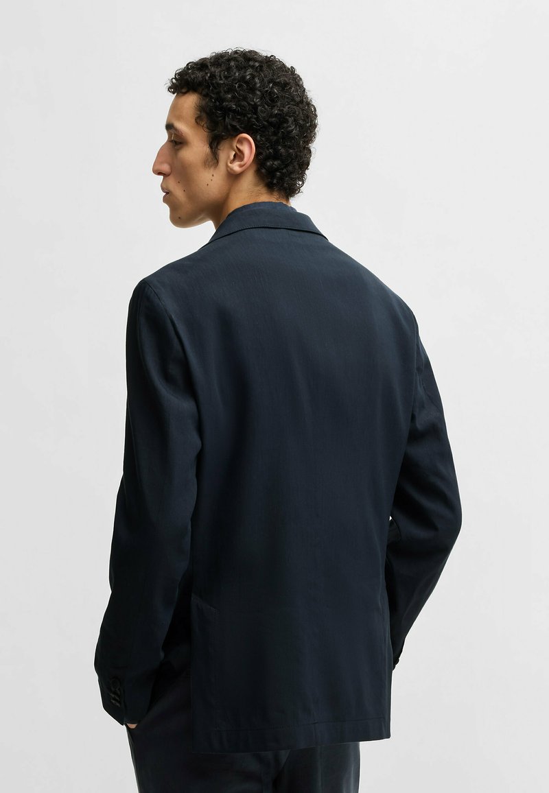 Navy Blazer aus glattem Stoff, mit klassischem Design, Schalkragen, langen Ärmeln und seitlichen Taschen, von hinten gezeigt.