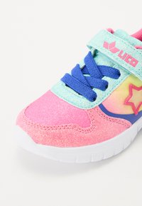Sapatilhas cor-de-rosa e verde-água com textura cintilante, atacadores azuis, uma pega de velcro e um destaque de estrela amarela na lateral. Sola de borracha branca.