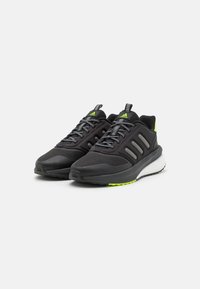 Zapatillas deportivas negras con parte superior de malla texturizada, acentos plateados, detalles reflectantes y una entresuela blanca con una suela verde.