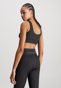 Czarny prążkowany stanik sportowy i legginsy z wysokim stanem, z logo Calvin Klein na pasa, o gładkiej teksturze i dopasowanym kroju.