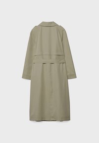 Trench-coat long beige avec manches longues, empiècement au dos et ceinture, présenté sur un fond gris clair uni.