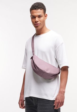 Marsupio in tessuto viola chiaro dalla texture liscia, con una tracolla lunga. Indossato a tracolla, regolabile per una vestibilità aderente.