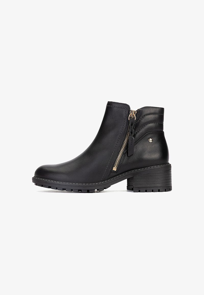 Bottine en cuir noir avec fermeture éclair latérale, talon bloc bas et semelle texturée pour l’adhérence.